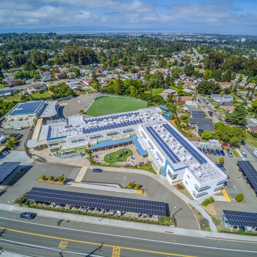 Aerial view of a Hayward Unified School District campus with rooftop and parking lot solar installations following project completion.